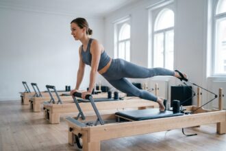 Femme pratiquant le Pilates sur un reformer dans un studio épuré et moderne à Paris Monceau